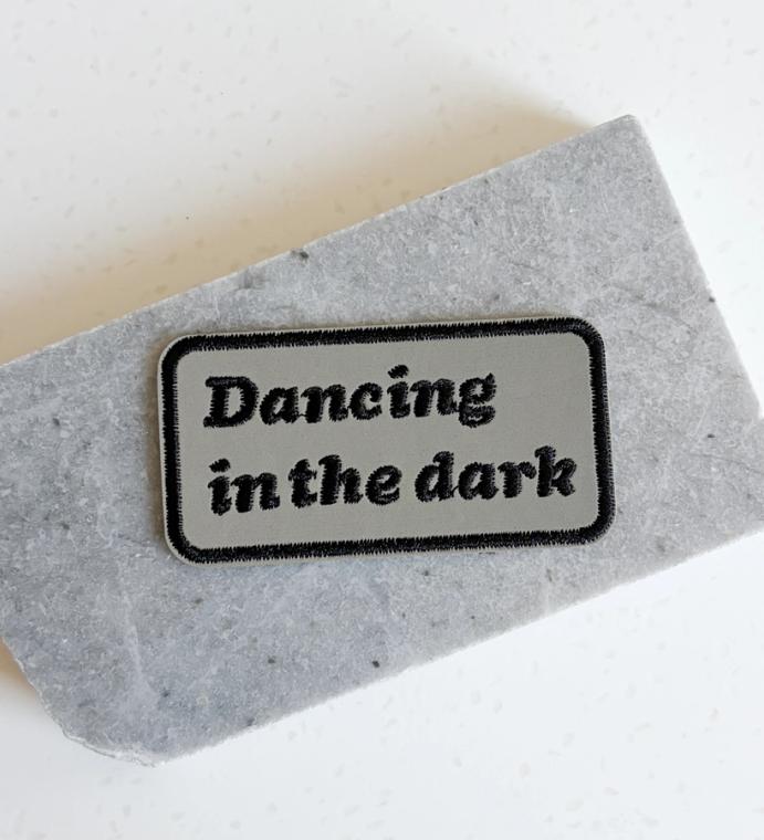 A patch that reads "dancing in the dark"