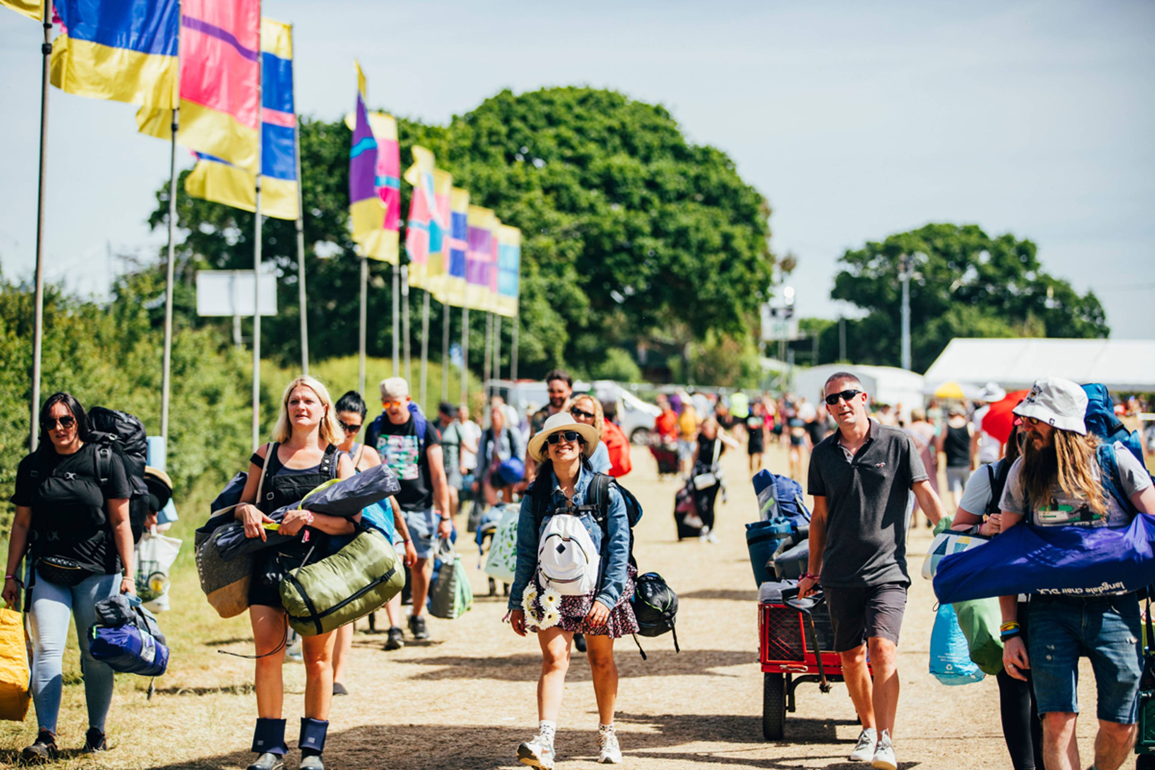 People walking at a festival with camping gear