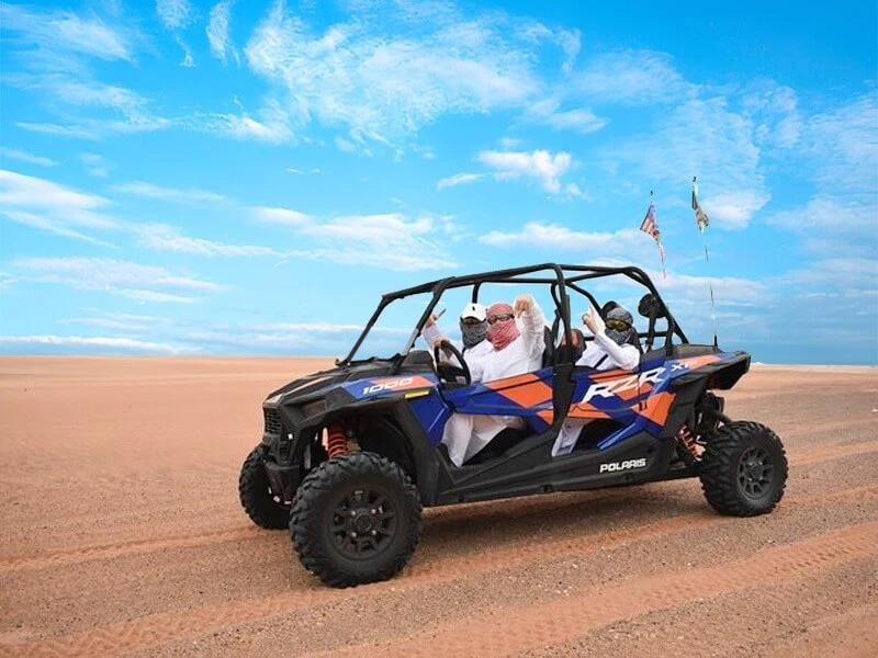 Polaris buggy and riders pausing for a photo on the dunes