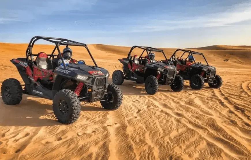Four-seater Polaris buggy driving over sand dunes
