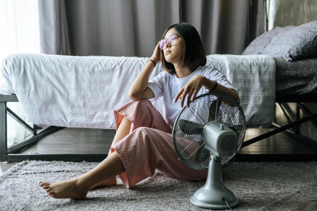 Woman lounging next to a fan