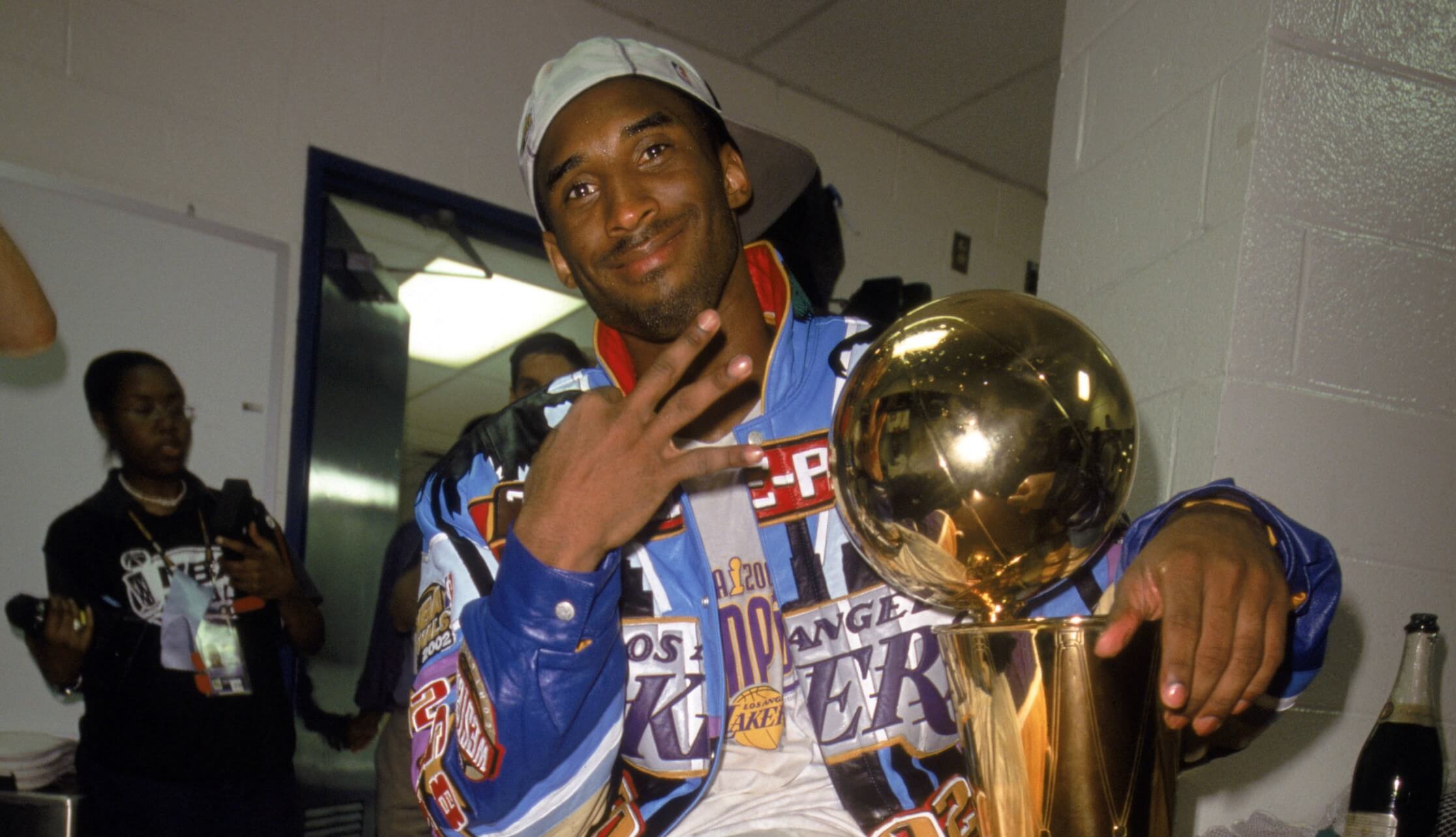 Athlete holding NBA championship trophy in locker room
