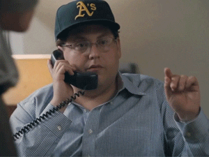 Man in A's cap on phone call, gesturing while speaking