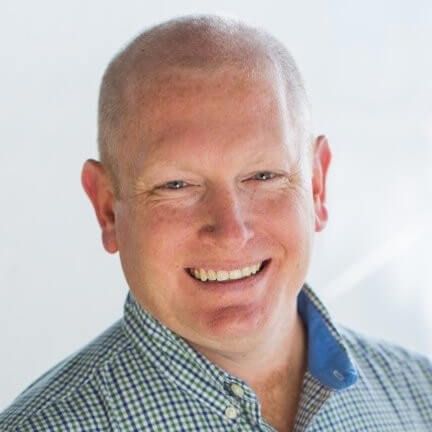 Smiling man in blue checkered shirt, professional headshot