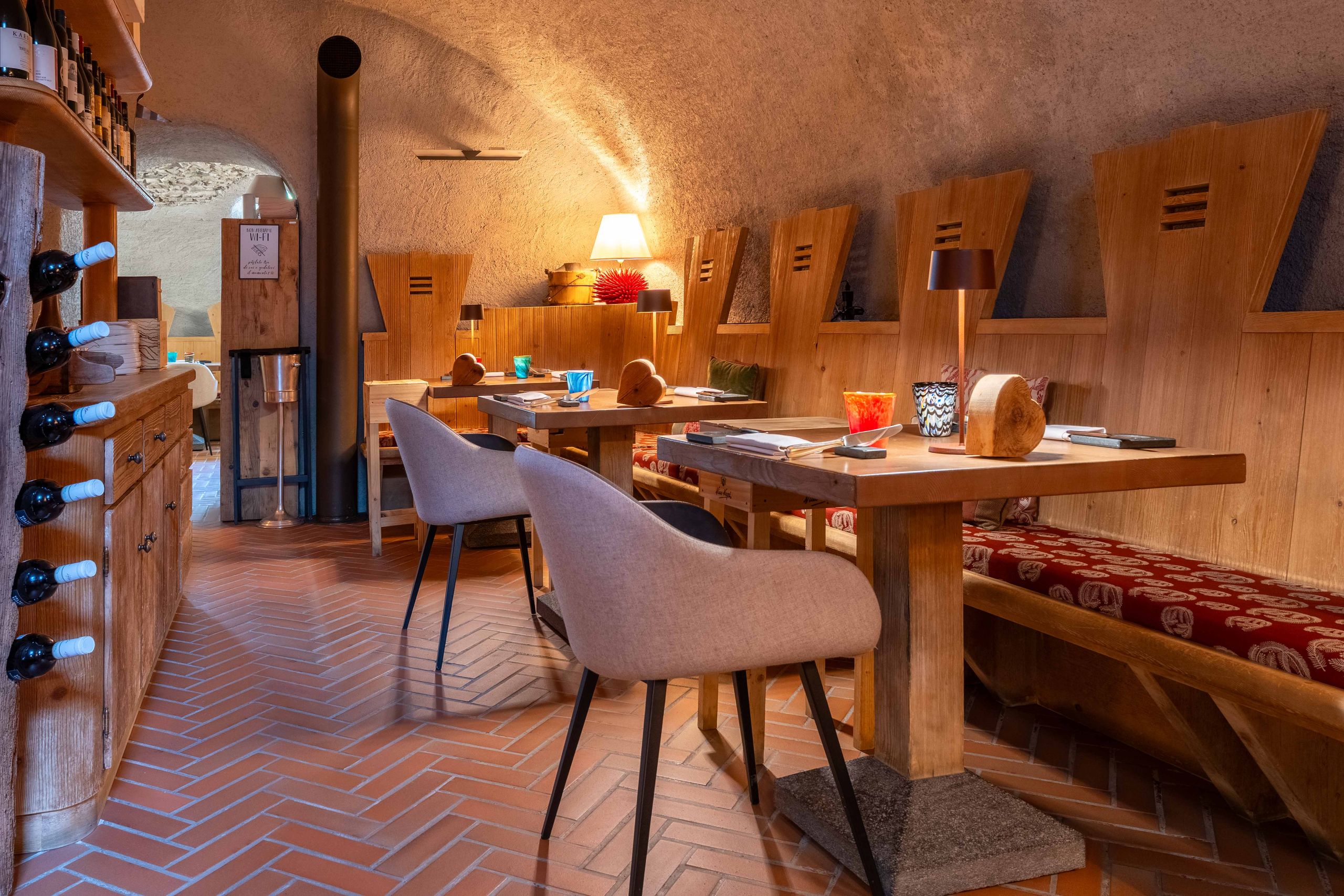 Sala interna dell'Osteria dei Magri a Bormio con tavoli in legno, sedie moderne e decorazioni calde.