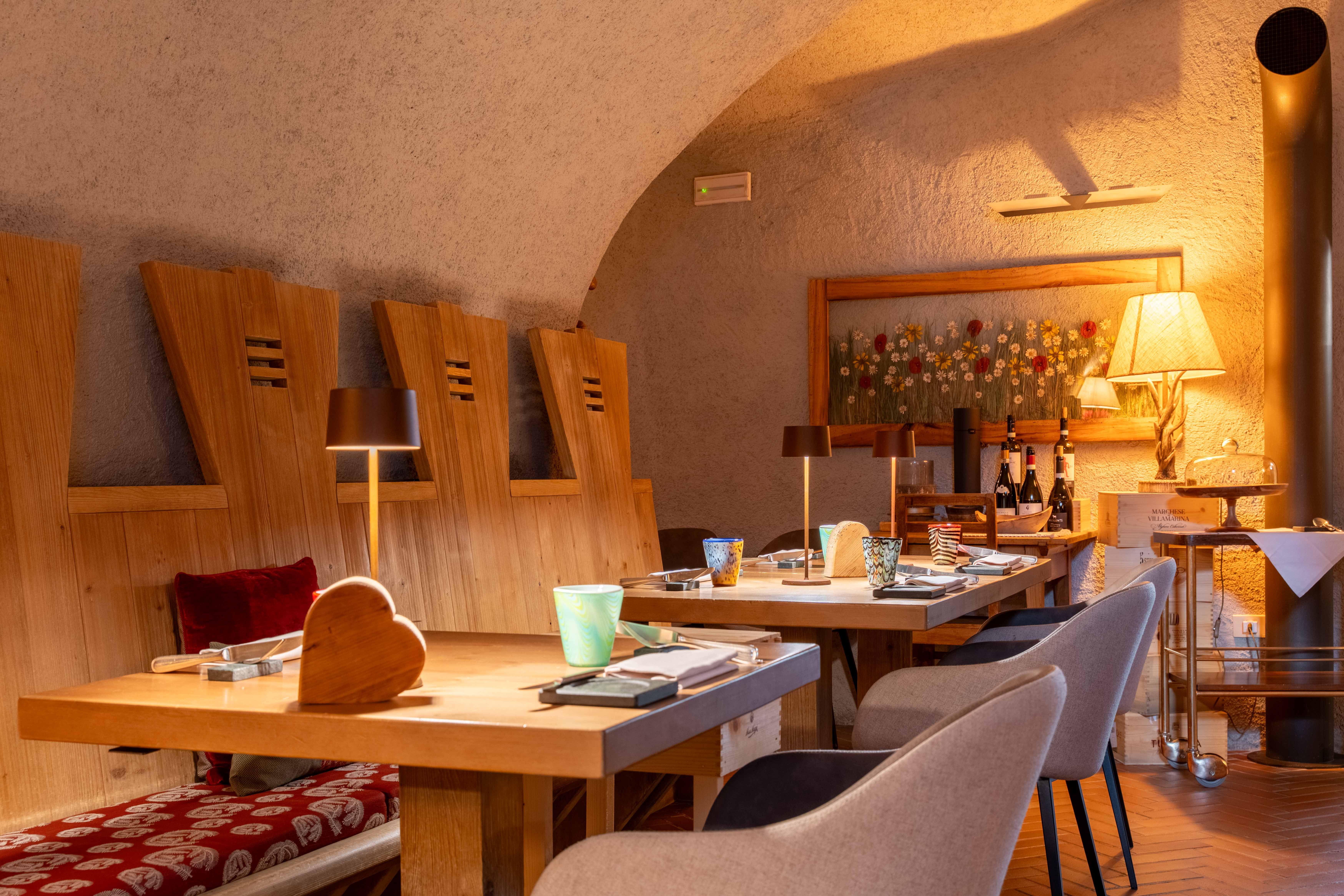 Interno rustico dell'Osteria dei Magri a Bormio con tavoli in legno apparecchiati e luci calde.