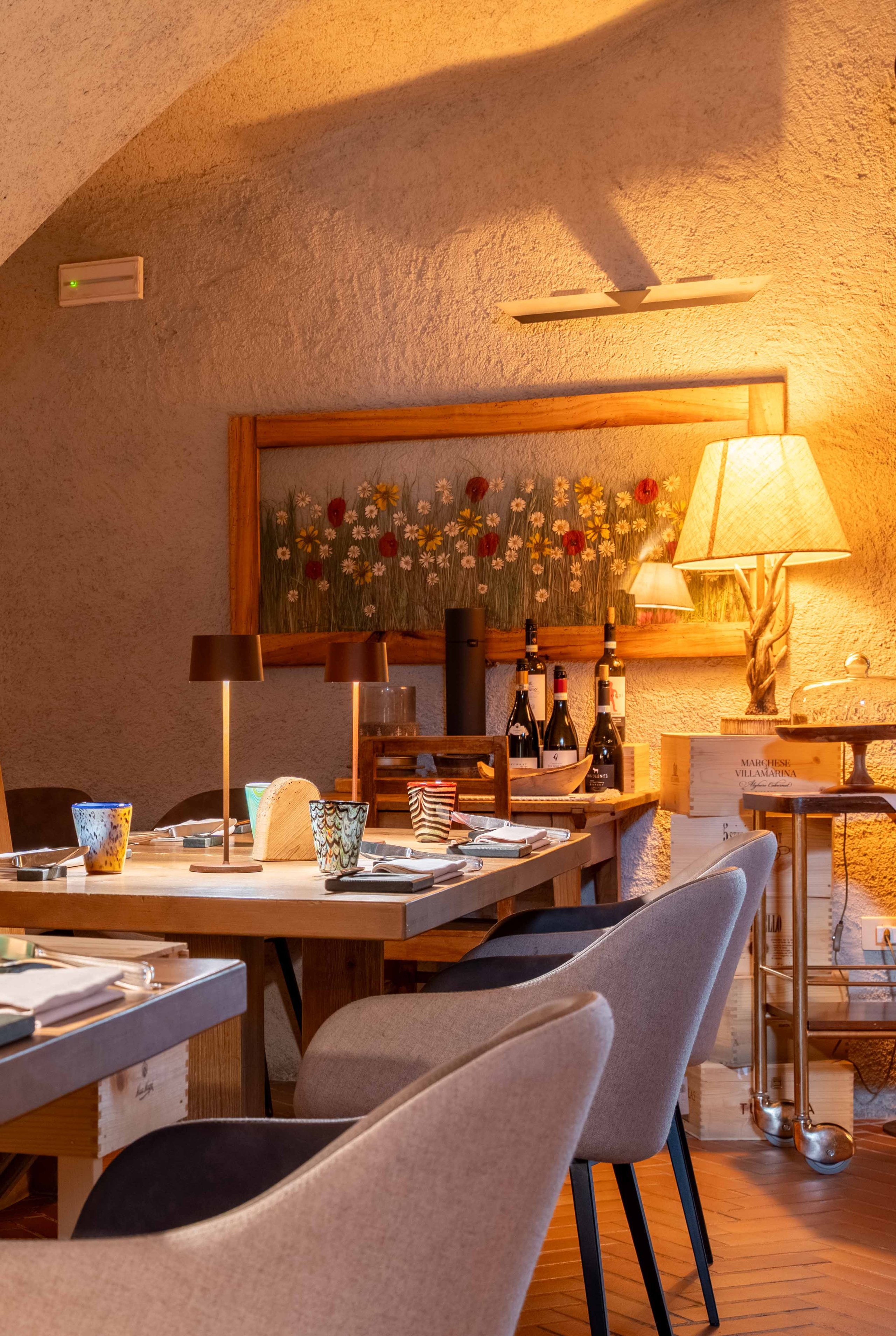 Interno rustico dell'Osteria dei Magri a Bormio con tavoli in legno apparecchiati e luci calde.