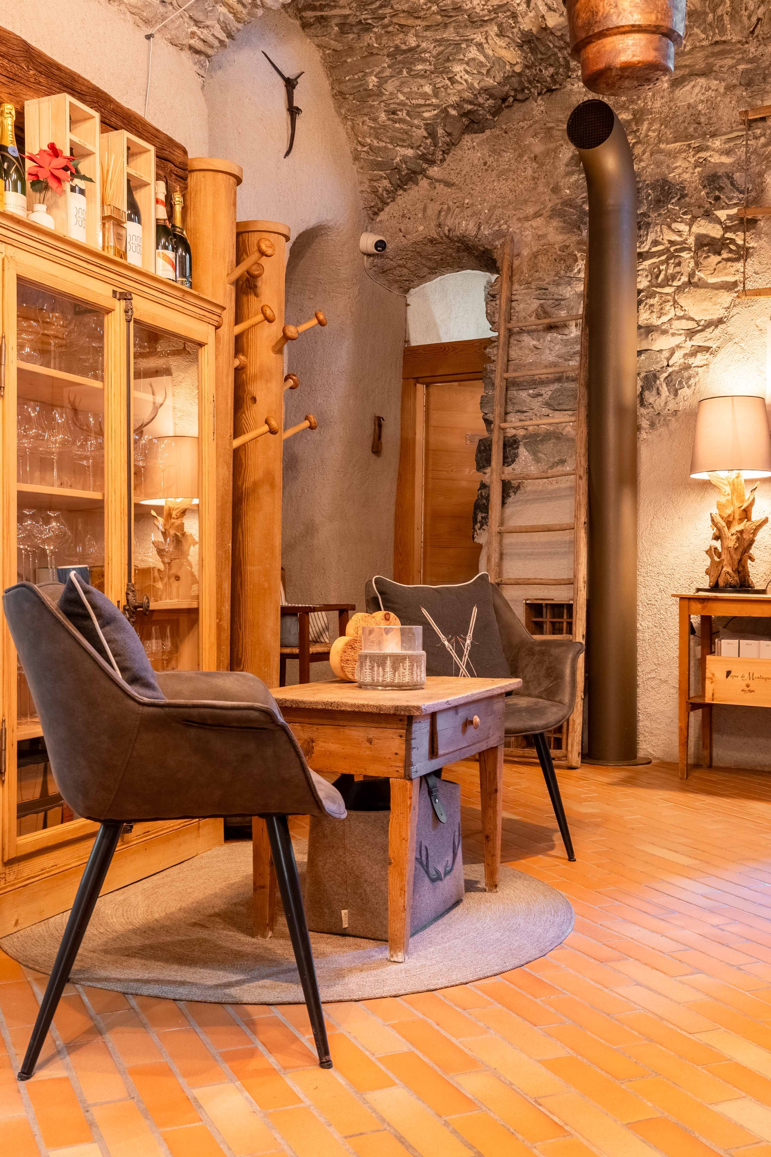Angolo accogliente dell'Osteria dei Magri con poltrone, tavolino in legno e pareti in pietra a volta.