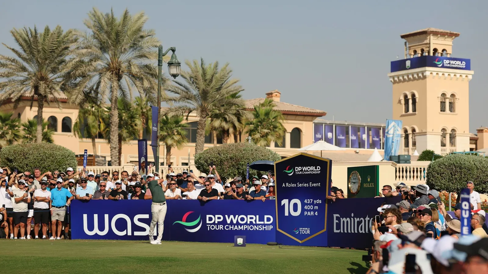 Toeschouwers en een speler bij de afslagplaats van hole 10 tijdens het DP World Tour Championship op Jumeirah Golf Estates