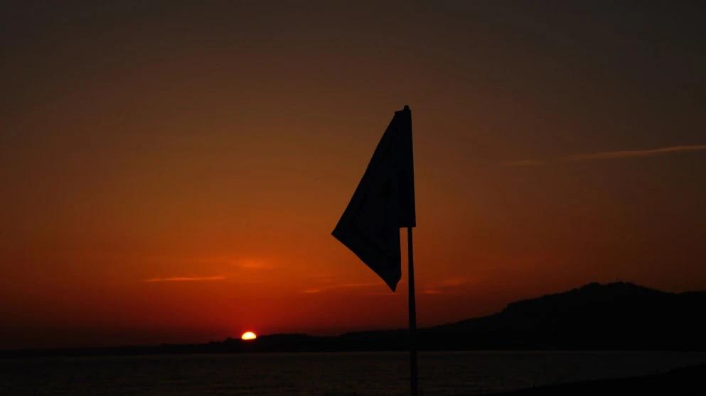 Een golfvlag silhouet bij zonsondergang, symbool voor de DP World Tour
