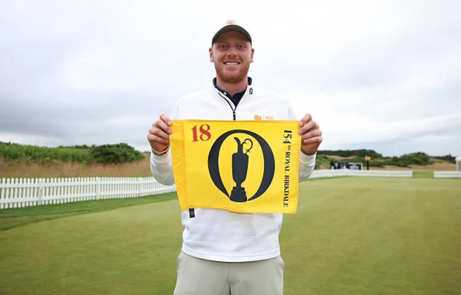 Nevill Ruiter houdt de vlag van The Open omhoog na zijn kwalificatie op Dundonald Links