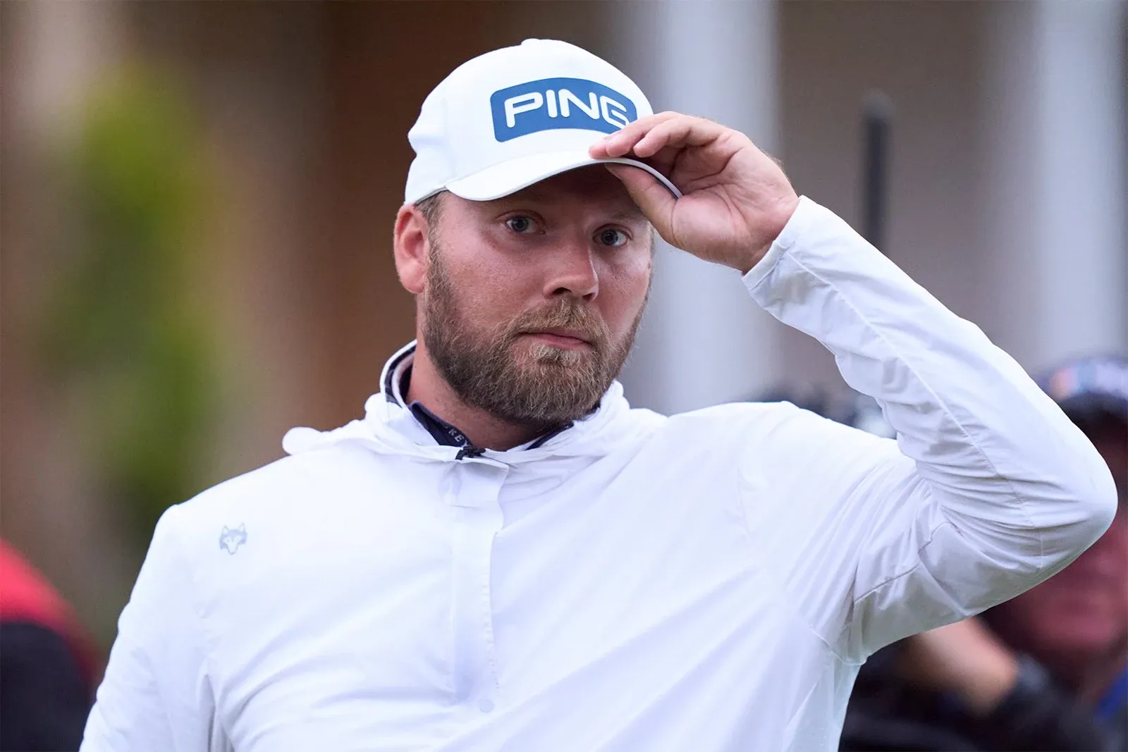 Dan Brown tijdens The Open Championship, met een witte PING-pet en witte jas