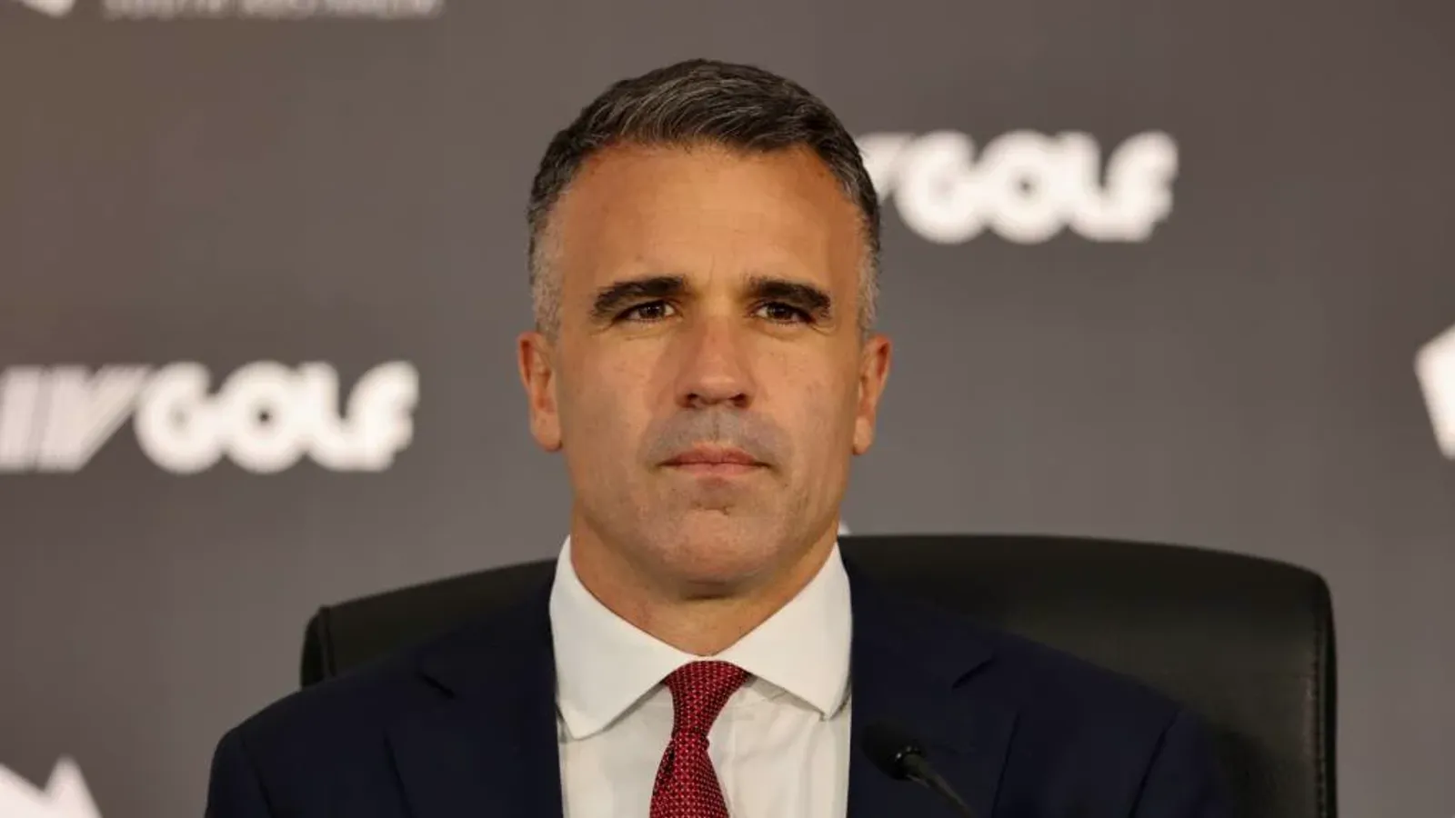 Premier Peter Malinauskas voor een achtergrond met het LIV Golf-logo