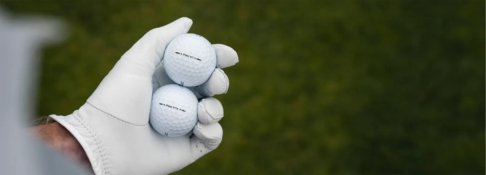 Hand met handschoen houdt een Titleist Pro V1 en een Pro V1x golfbal vast