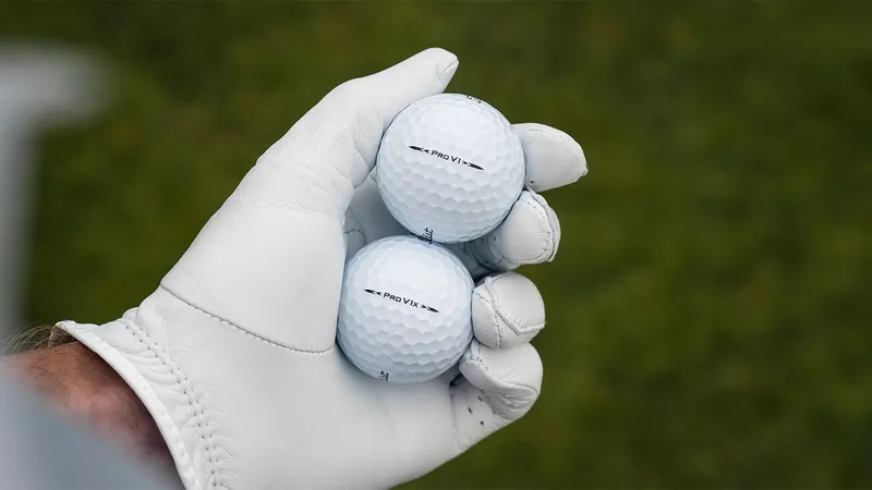 Hand met handschoen houdt een Titleist Pro V1 en een Pro V1x golfbal vast
