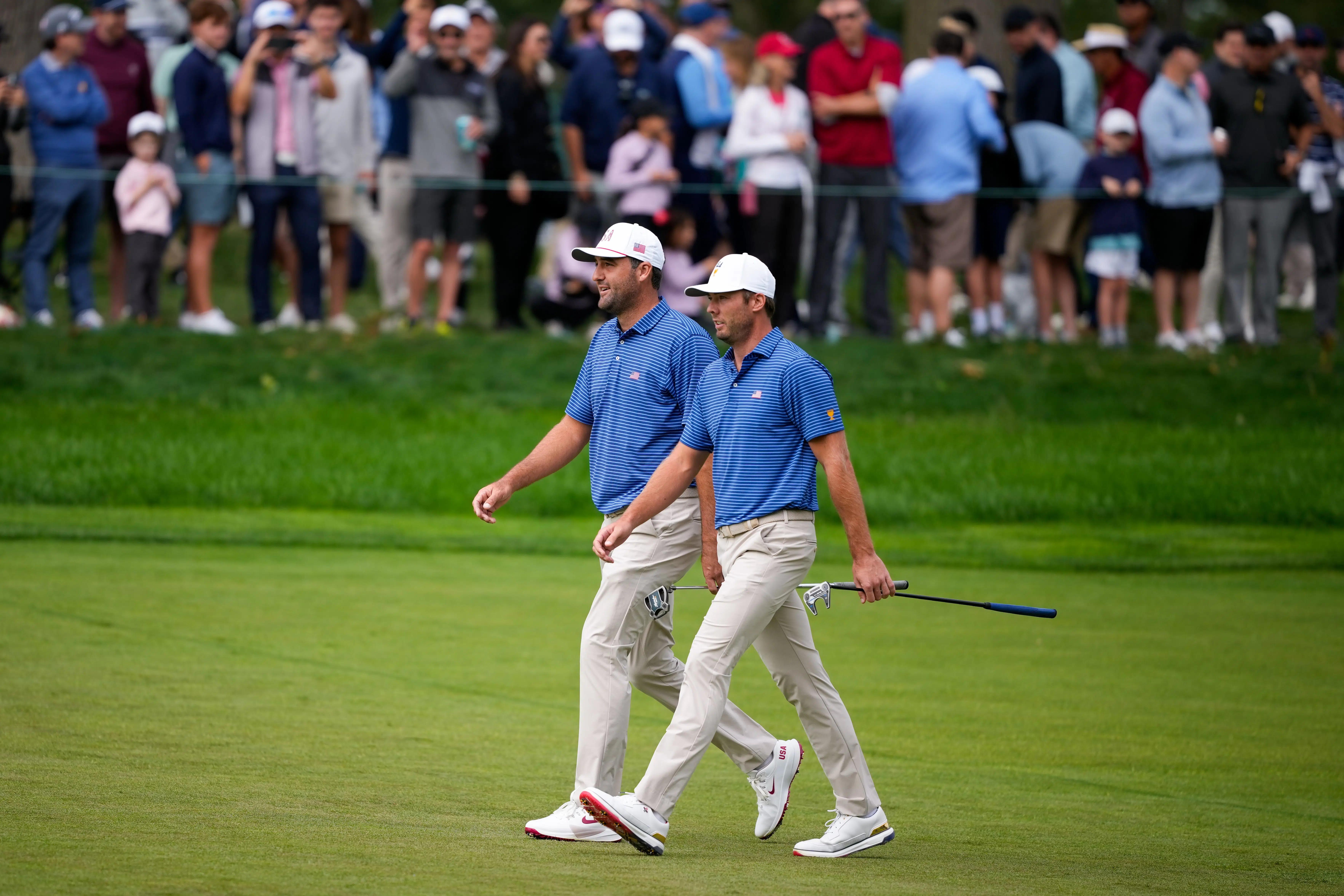Scottie Scheffler en Sam Burns lopen over de fairway tijdens de Presidents Cup 2026 op Medinah Country Club