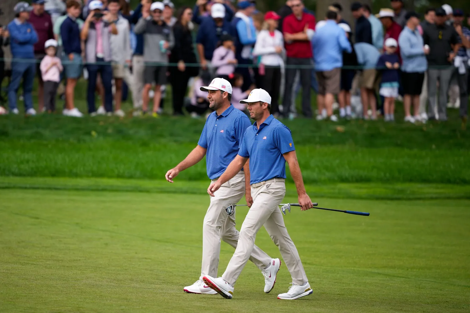 Scottie Scheffler en Sam Burns lopen over de fairway tijdens de Presidents Cup 2026 op Medinah Country Club