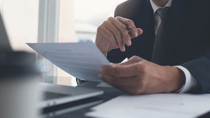 Business professional reviewing payroll and compliance documents at a desk.