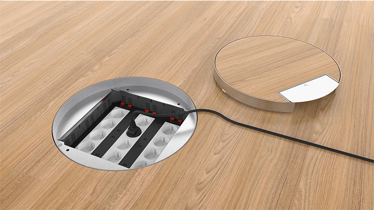 Open floor box in a wooden floor with a plugged-in cable