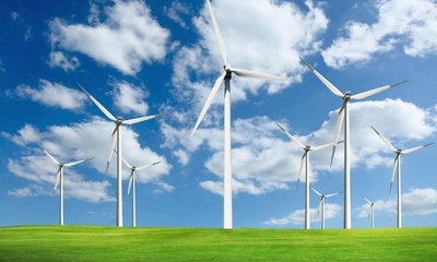 An image of windmills on grass with a partly cloudy sky background