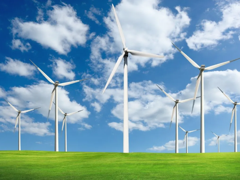 An image of windmills on grass with a partly cloudy sky background