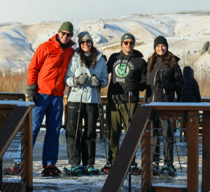 four people smiling for the camera on skis outside