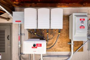 A variety of electrical equipment for the building including inverters, meters, conduit, and breaker box