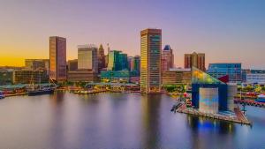 A view of the Baltimore, Maryland skyline and Inner Harbor with waterfront buildings and boats at sunset