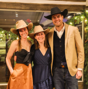 three people smiling for the camera, all wearing cowboy hats