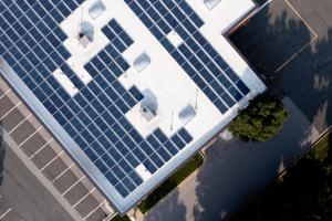 Image of solar panels on the roof of a building with parking lots visible around it