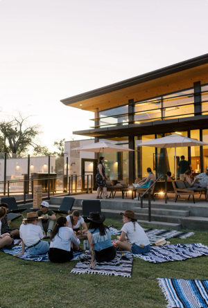 A group of people sitting on blankets in grass