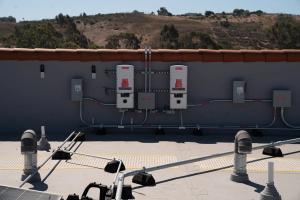 A variety of electrical equipment for the building including inverters, meters, conduit, and breaker box