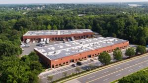 Image of two commercial buildings with solar panels on both of the roofs, next to a road