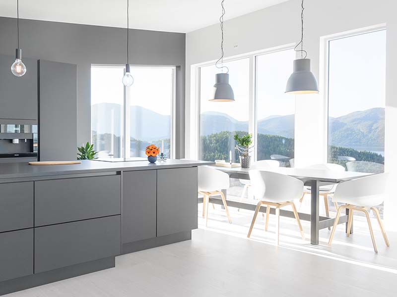 moderne kjøkken med grå benkeskap og hvite spisestoler. store vinduer med utsikt