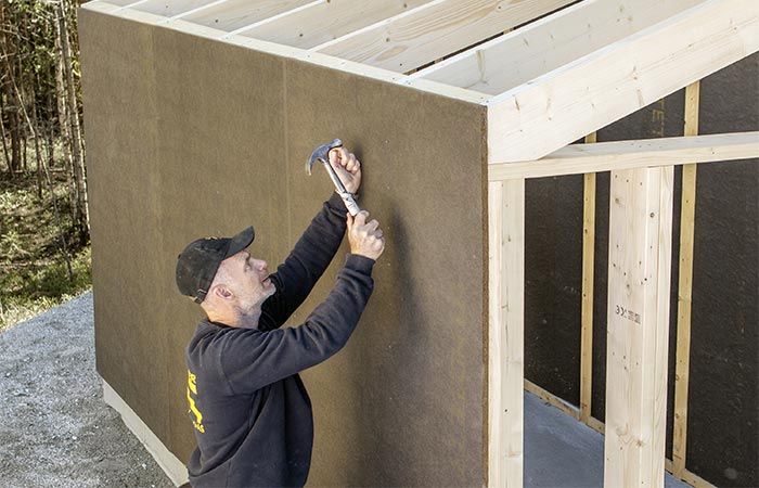 Mann som setter opp vindsperre på hus