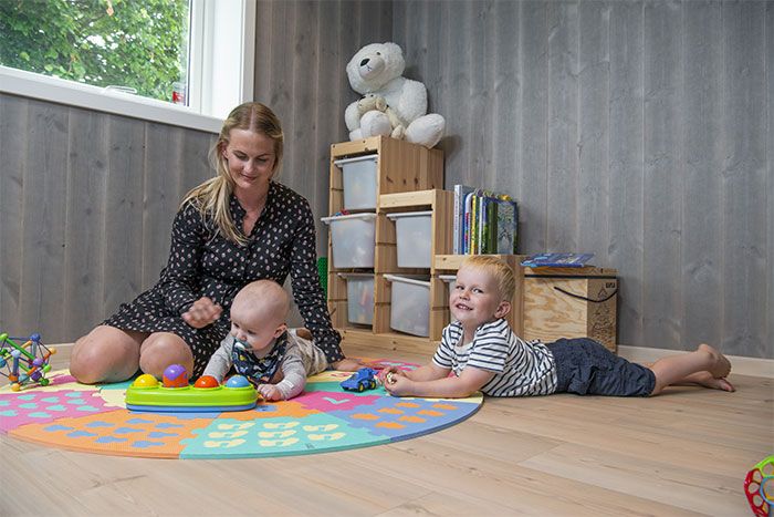 En dame og to barn som leker på et gulv