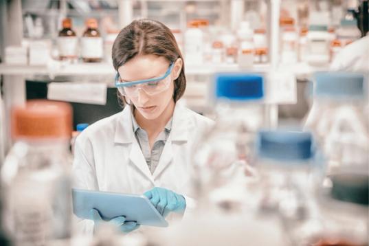 Chemist wearing safety glasses and using tablet pc