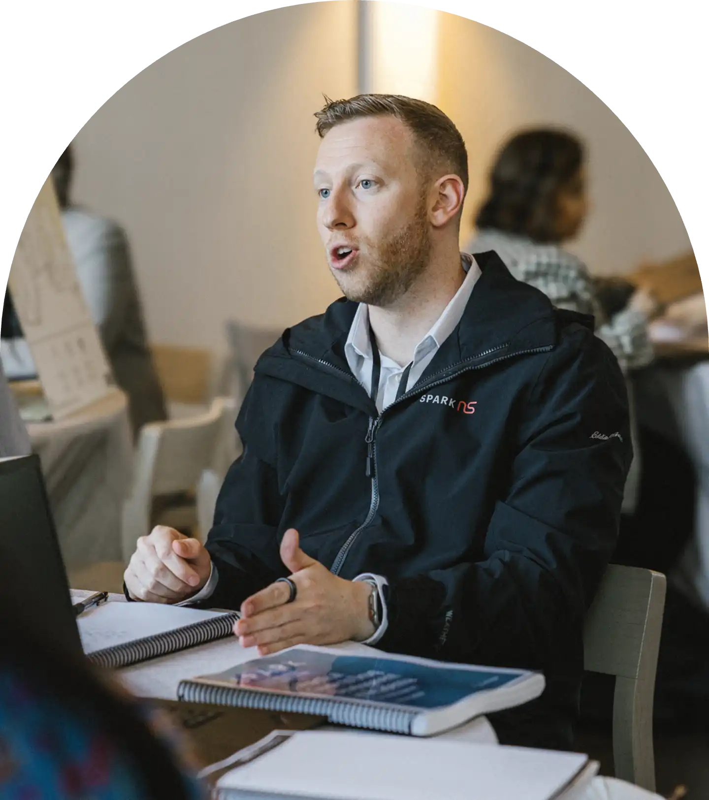 A man gestures across as they discuss with the person across from them