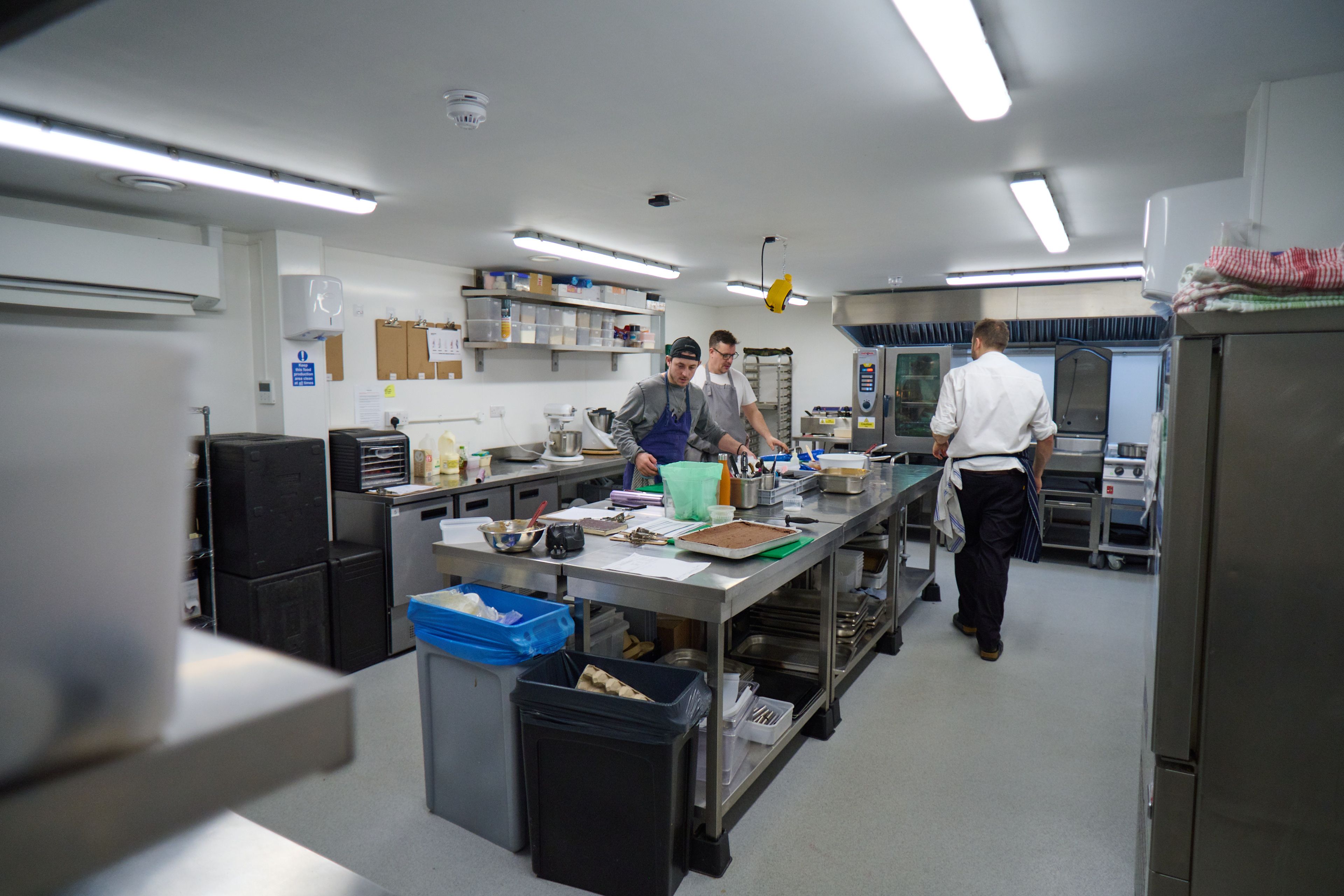 Three chefs at work in a professional kitchen.