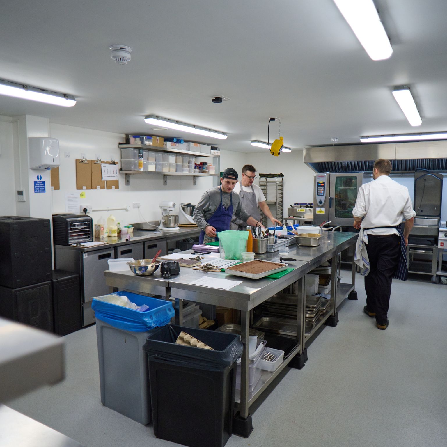 Three chefs at work in a professional kitchen.