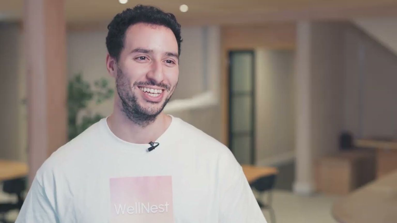 A smiling man wearing a white t-shirt with the "WellNest" logo.