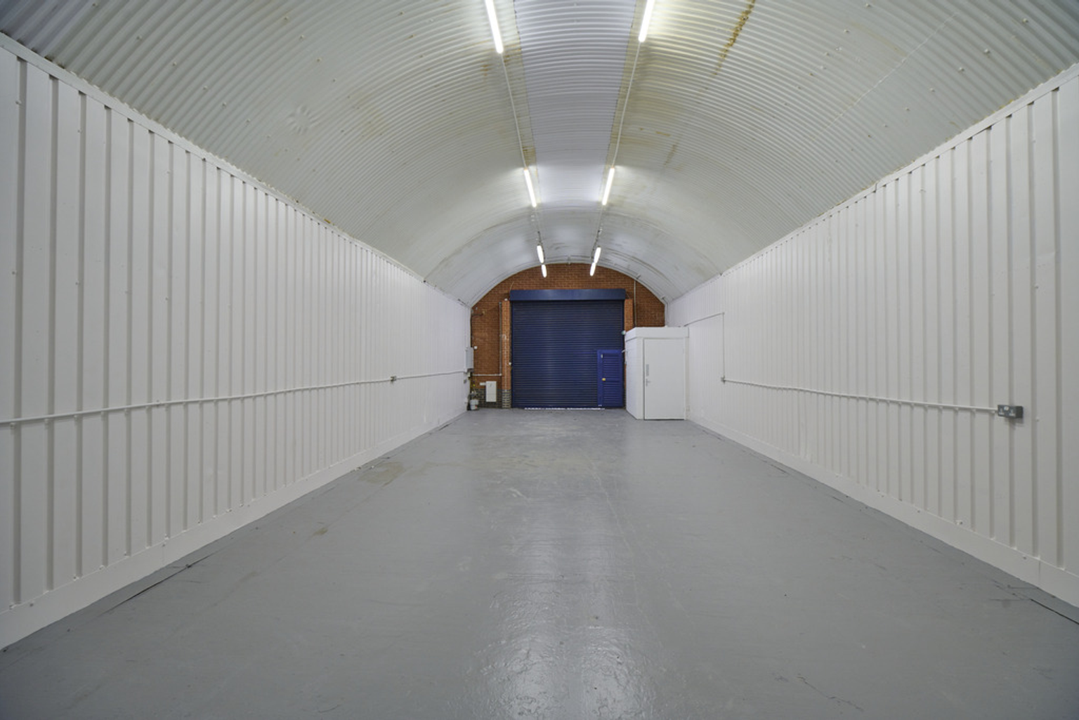 An empty arch with white lining and a WC cubicle to the back.