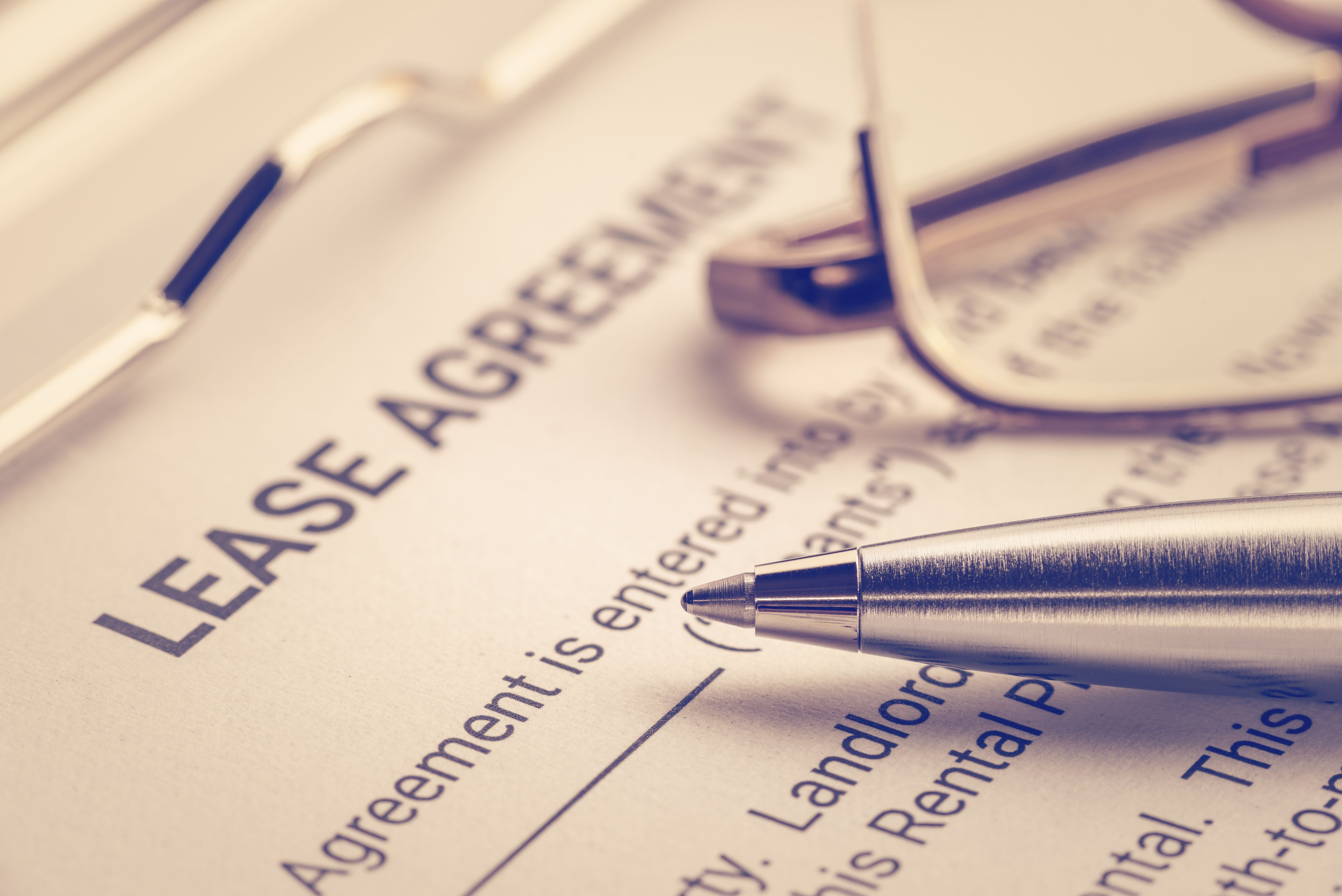 A lease agreement document with a pen and glasses.