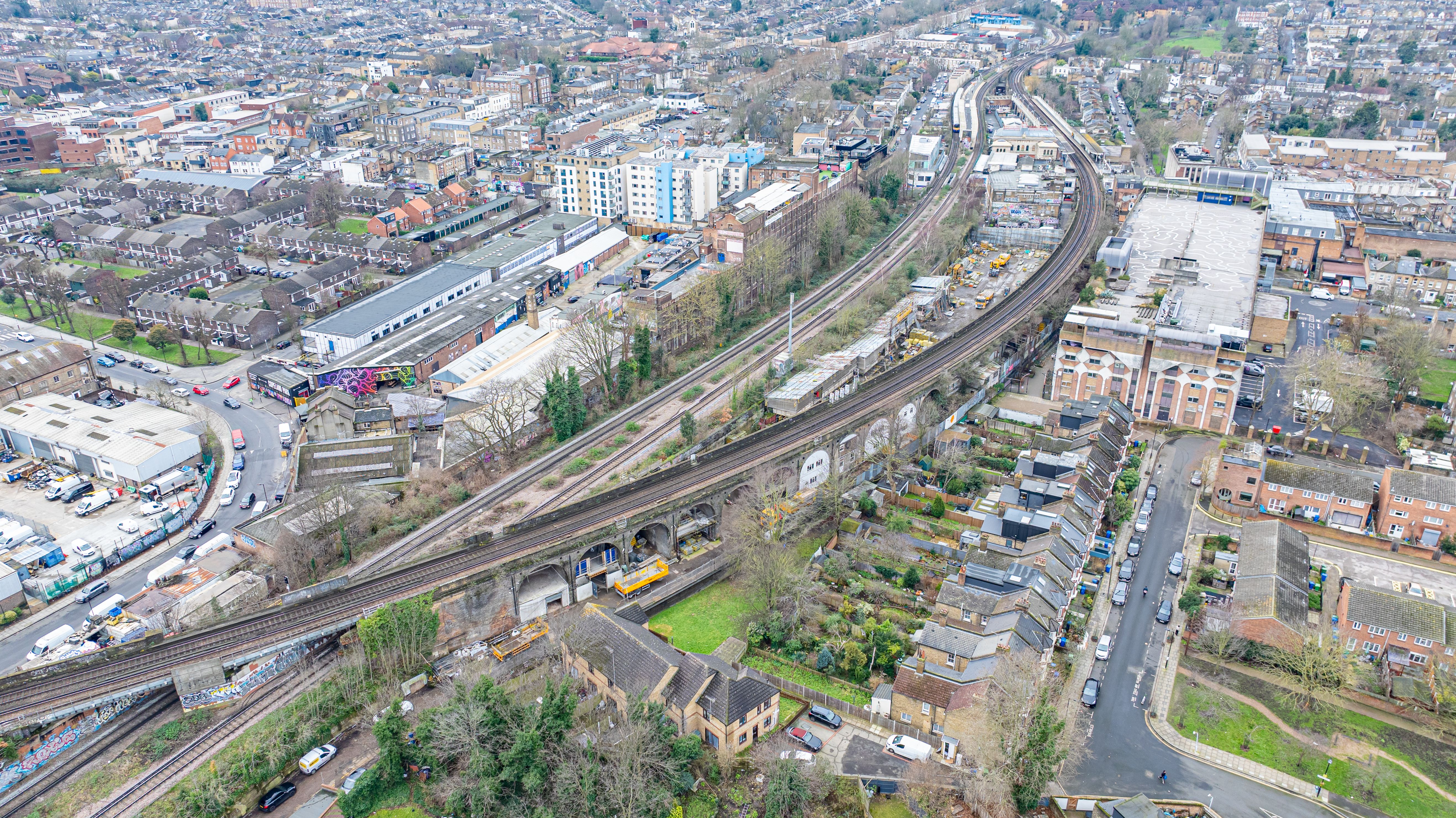 Aerial view of an urban area with multiple railway tracks, including a viaduct, alongside residential and commercial buildings.