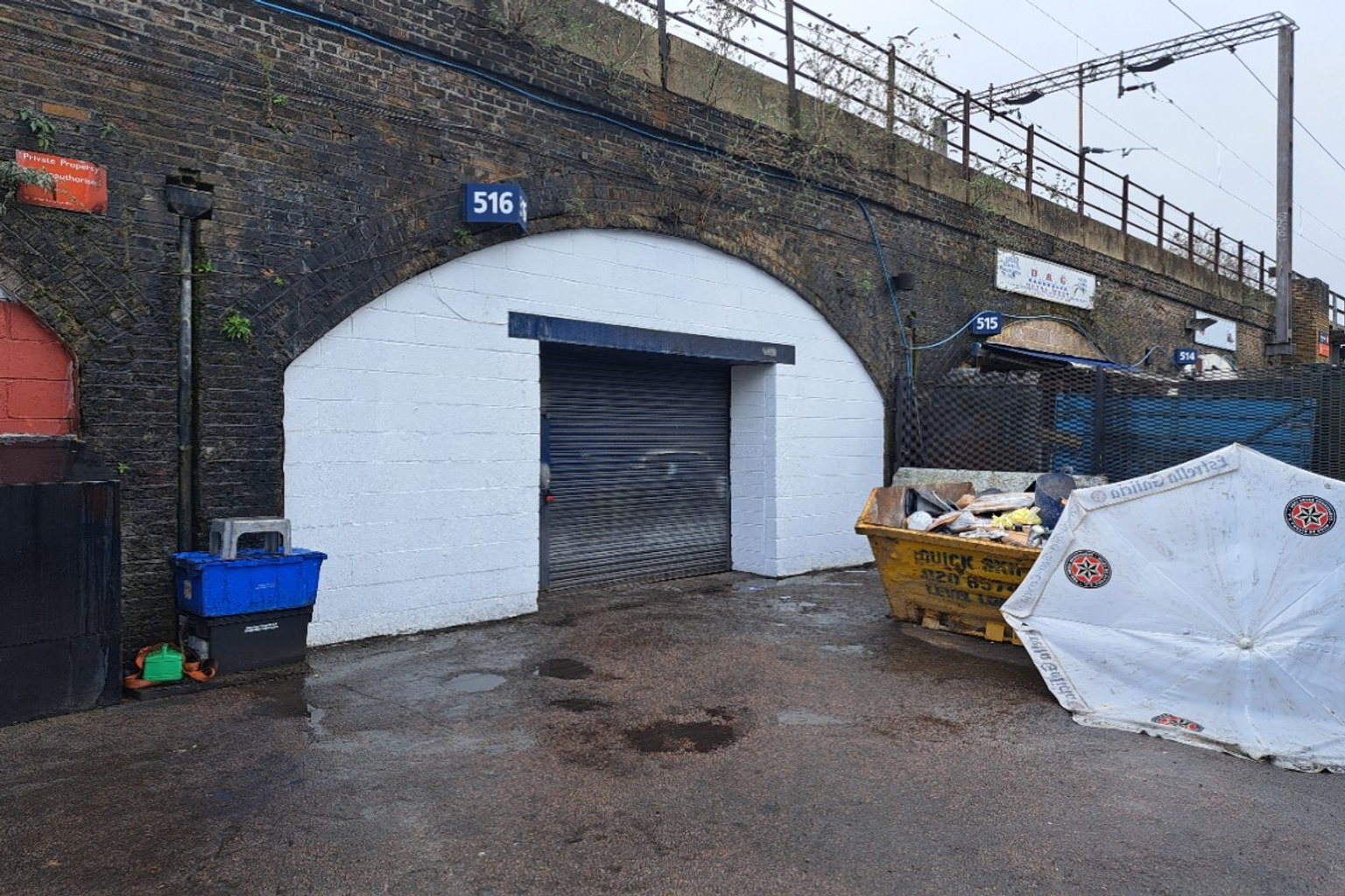 The front of an arch, with high level glazing, an open electric roller shutter entrance big enough for vehicle access, and a pedestrian door.