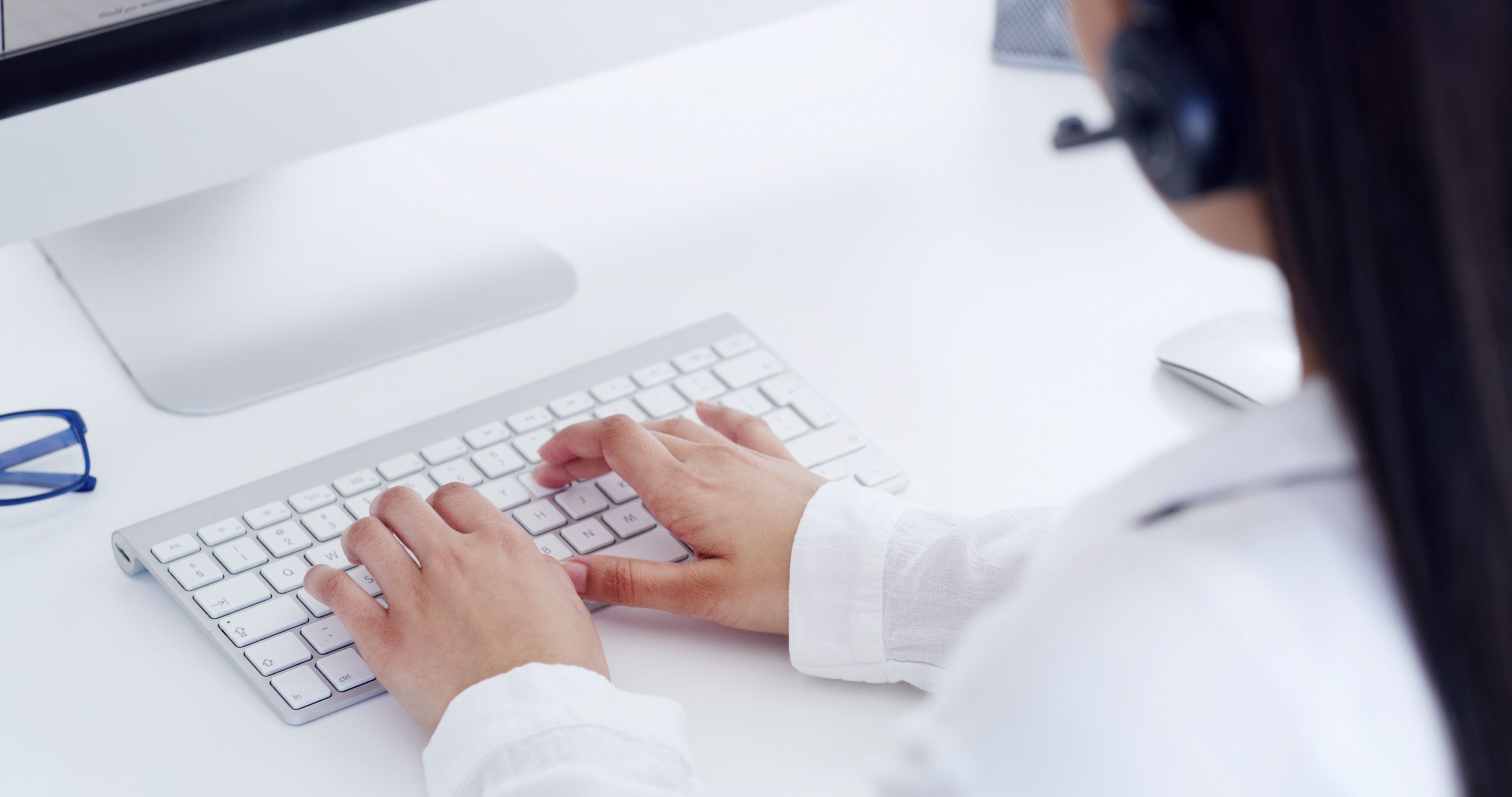 Person in a headset typing on a keyboard.