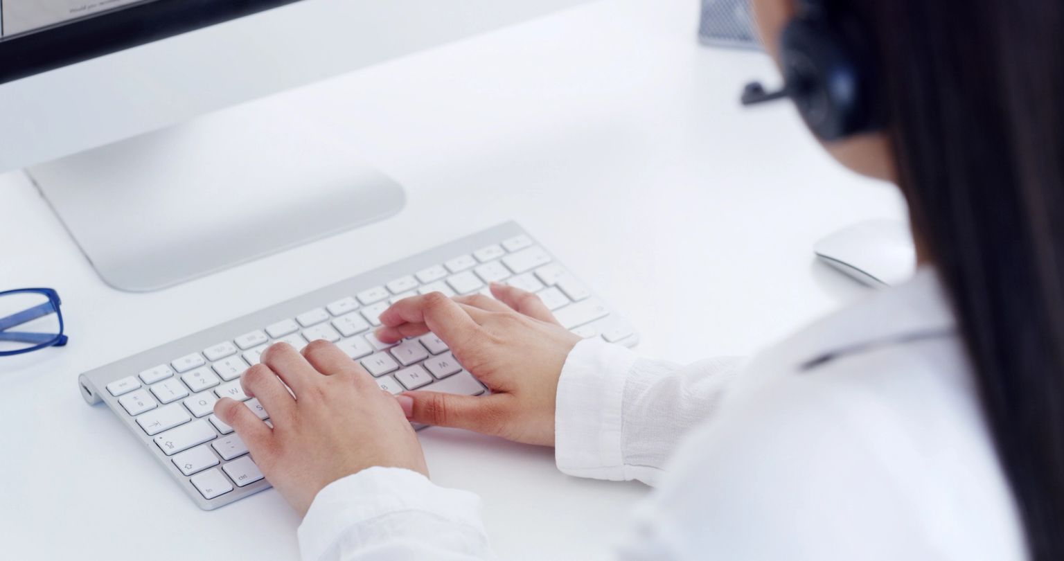 Person in a headset typing on a keyboard.