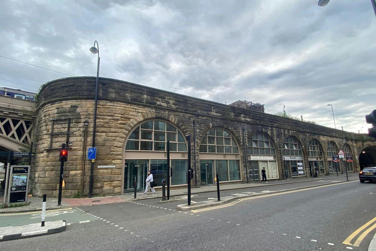 Stone railway arches converted into shops lining a street under an overcast sky.