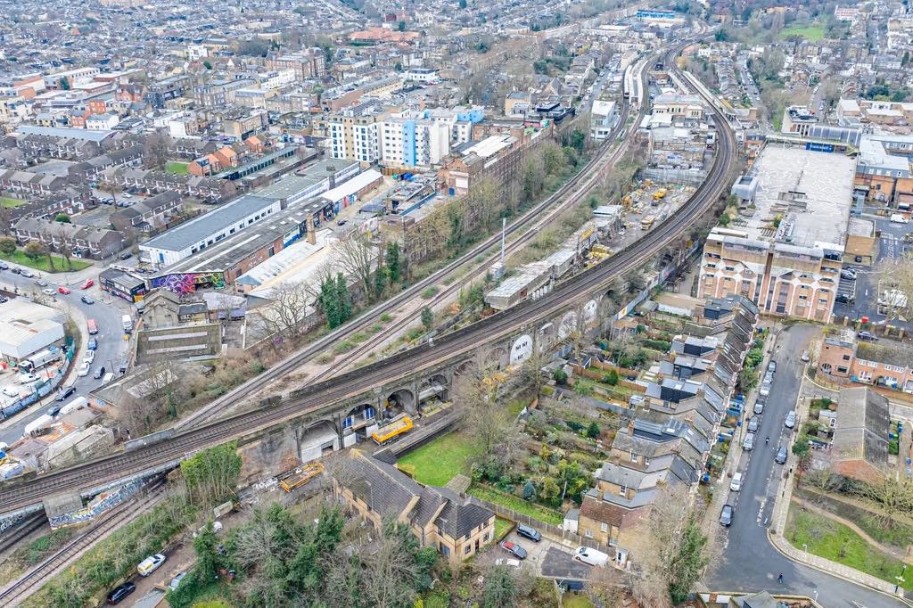 Aerial view of a dense urban area with a curving railway viaduct, buildings, and roads.