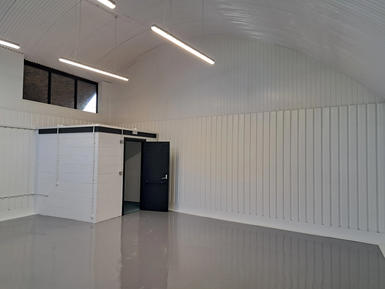 An empty arch with white lining and a WC cubicle to the back.